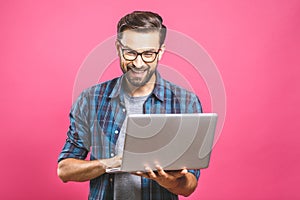 Confident business expert. Confident young handsome man in shirt holding laptop and smiling while standing against pink background