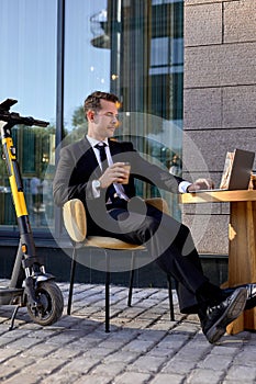 Confident business man in formal wear sit working on laptop in outdoor cafe