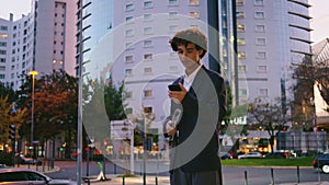 Confident business man looking phone at sunset city. Serious guy waiting street