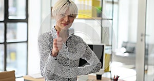 Confident business woman doing thumbs up gesture of approval in office