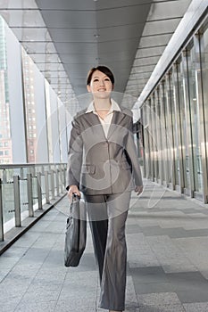 Confident business woman holding briefcase and walking