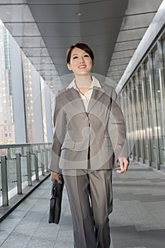 Confident business woman holding briefcase and walking