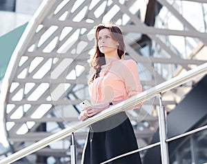 Confident business woman standing on the balcony of a modern office building