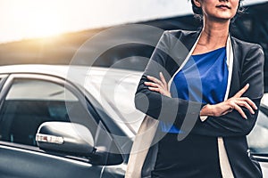 Confident business woman standing beside the car.