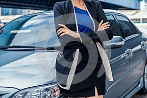 Confident business woman standing beside the car.