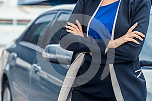 Confident business woman standing beside the car.