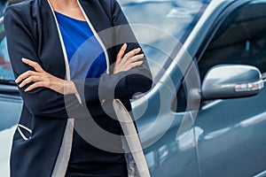 Confident business woman standing beside the car.