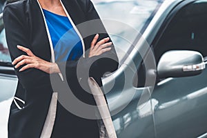 Confident business woman standing beside the car.