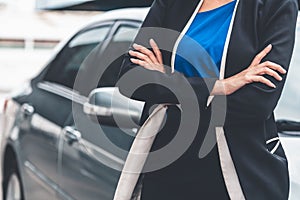 Confident business woman standing beside the car.