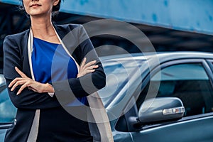 Confident business woman standing beside the car.