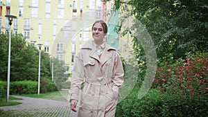 Confident business woman walking down street, smiling, looking at camera. Beautiful career girl in coath going around