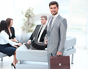 Confident businessman with briefcase standing in the lobby of the office.