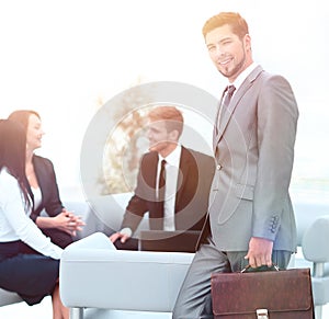 Confident businessman with briefcase standing in the lobby of the office.