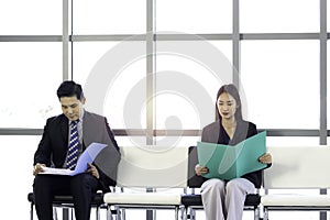 Confident businessman and businesswoman holding file folder during sitting on chair, waiting for job interview in reception hall