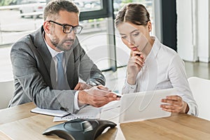 confident businessman and businesswoman looking at tablet together