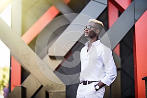 Confident businessman. Confident young afro american man standing outdoors with modern city in the background