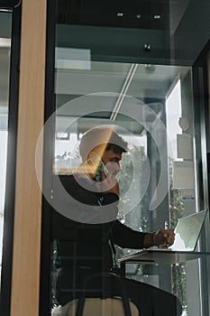 Confident businessman discussing marketing strategies for business growth and profitability in soundproof phone booth.