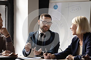 Confident businessman discussing project strategy with colleagues at meeting