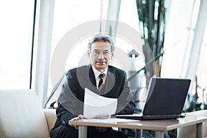 Confident businessman with documents on a laptop