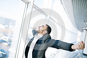 Confident businessman enjoys his success raising his hands and fists up