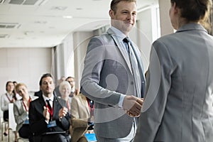 Confident businessman greeting public speaker during seminar