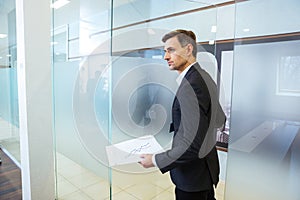 Confident businessman holding documents and entering the office