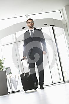 Confident businessman with luggage entering convention center