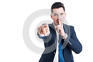 Confident businessman making keep a secret and silence gesture