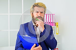 Confident businessman in office. Bearded handsome man with notepad. Pensive Manager at workplace.