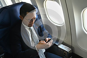 Confident businessman passenger checking news on smart phone, using wireless connection on board during flight