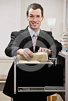 Confident businessman searches through file drawer