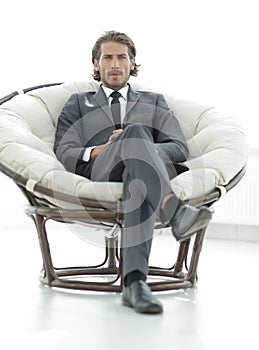 Confident businessman sitting in a large comfortable chair.