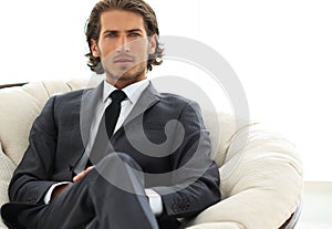 Confident businessman sitting in a large comfortable chair.