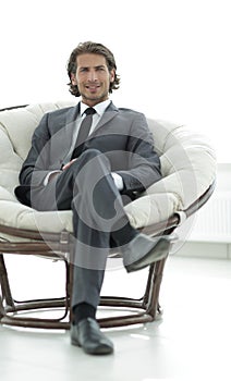 Confident businessman sitting in a large comfortable chair.