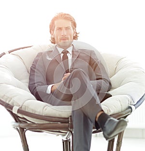 Confident businessman sitting in a large comfortable chair.