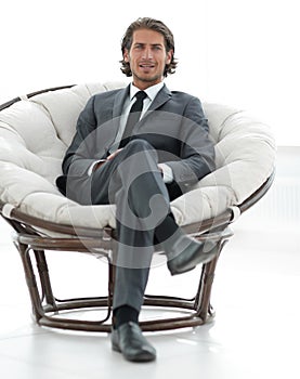 Confident businessman sitting in a large comfortable chair.