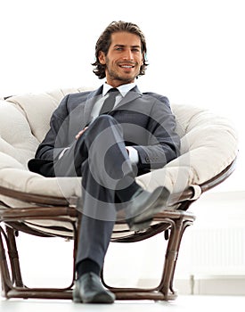 Confident businessman sitting in a large comfortable chair.