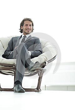 Confident businessman sitting in a large comfortable chair.