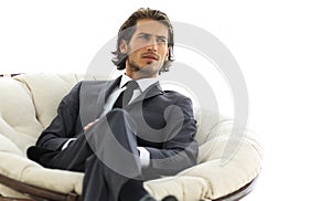 Confident businessman sitting in a large comfortable chair.