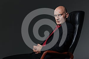 Confident businessman sitting in office chair and looking at camera