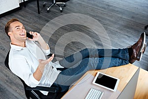 Confident businessman sitting and talking on mobile phone at workplace