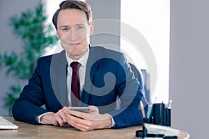 Confident businessman with smartphone looking at camera