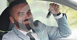 Confident businessman smiling to camera and showing key of his new car, close up