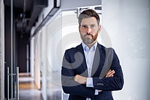 Confident businessman standing with arms crossed in office
