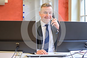 Confident businessman talking on a phone in an office