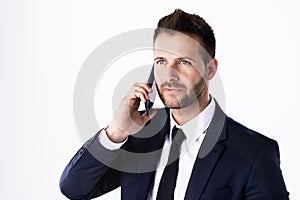 Confident businessman talking with somebody on his mobile phone while standing at isolated white background