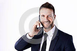 Confident businessman talking with somebody on his mobile phone while standing at isolated white background