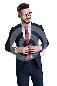 Confident businessman unbuttoning his jacket and looking away
