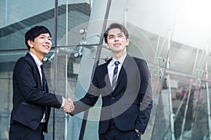 confident businessmen shaking hands and smiling