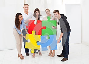 Confident businesspeople joining puzzle pieces